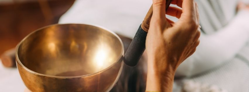 A person using a Tibetan singing bowl for sound healing, symbolizing emotional healing and mindfulness practices.